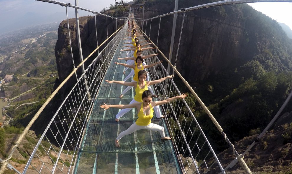 Las mujeres practican yoga durante una actuación en un puente de vidrio en el Parque Nacional Shiniuzhai, en el condado chino de Pingjiang. REUTERS