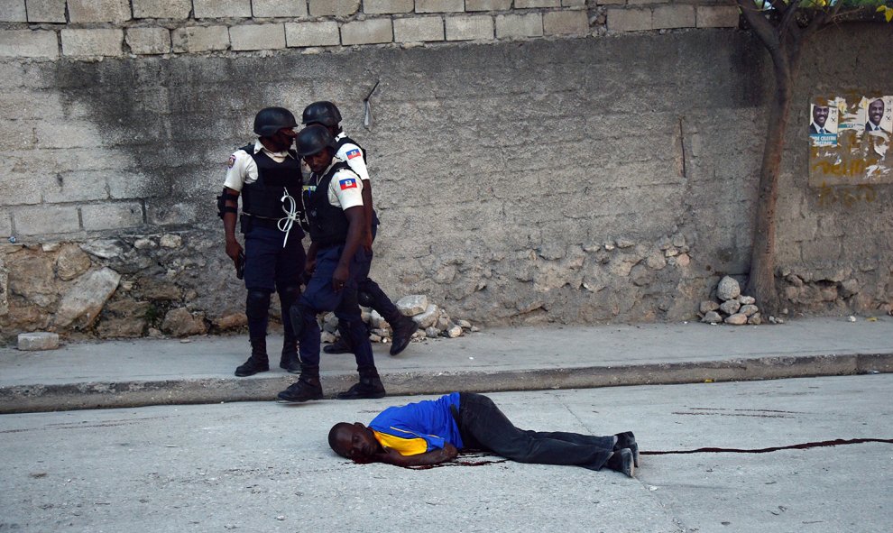 Policias haitianos caminan junto a un partidario del candidato presidencial Jean Charles Moise, disparado durante una manifestación en Port-au-Prince.- HECTOR RETAMAL (AFP)