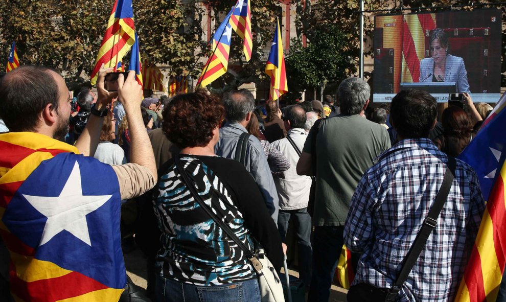 Miembros de la ANC y otras entidades soberanistas siguen a través de una gran pantalla instalada ante el Parlament el debate. /EFE