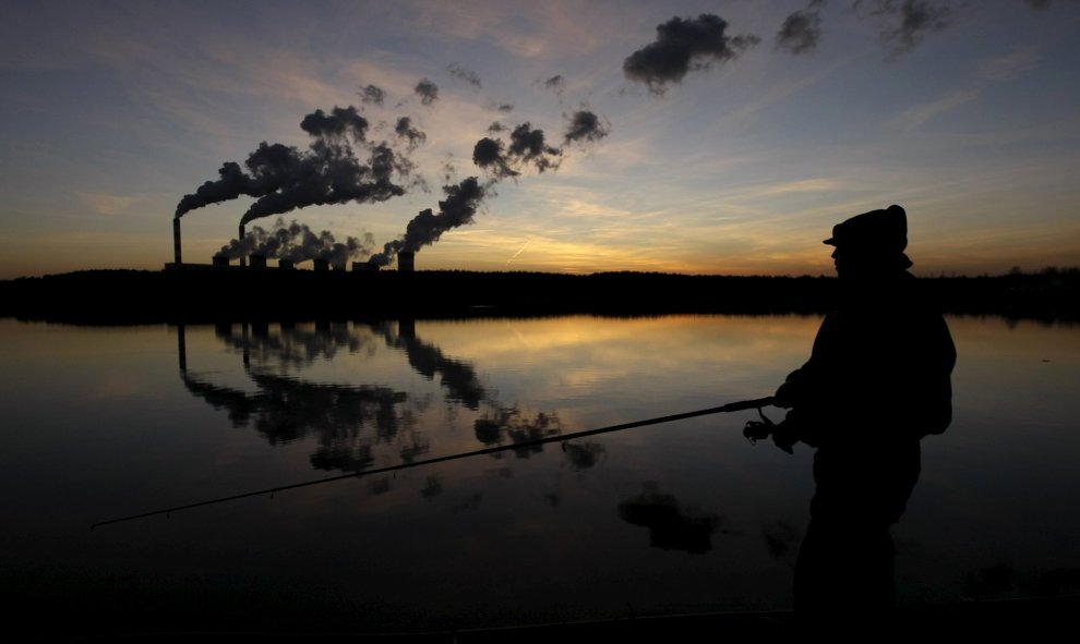 Un hombre pesca en un lago artificial fuera de la central eléctrica Belchatow, en Polonia. REUTERS
