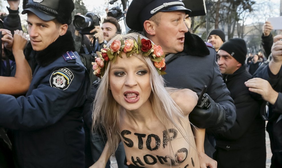 Un policía ucraniano arresta a una activista del movimiento Femen durante una protesta delante del Parlamento en Kiev (Ucrania) contra la homofobia y para reclamar que se corrija el Códido Laboral del país para prevenir y actuar contra la discriminación.