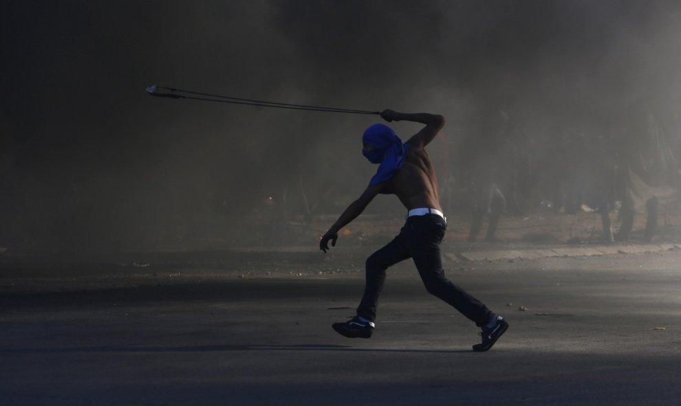 Un joven palestino lanza piedras contra soldados israelíes durante una protesta en Beit El, a las afueras de la ciudad cisjordana de Ramala. EFE/ALAA BADARNEH
