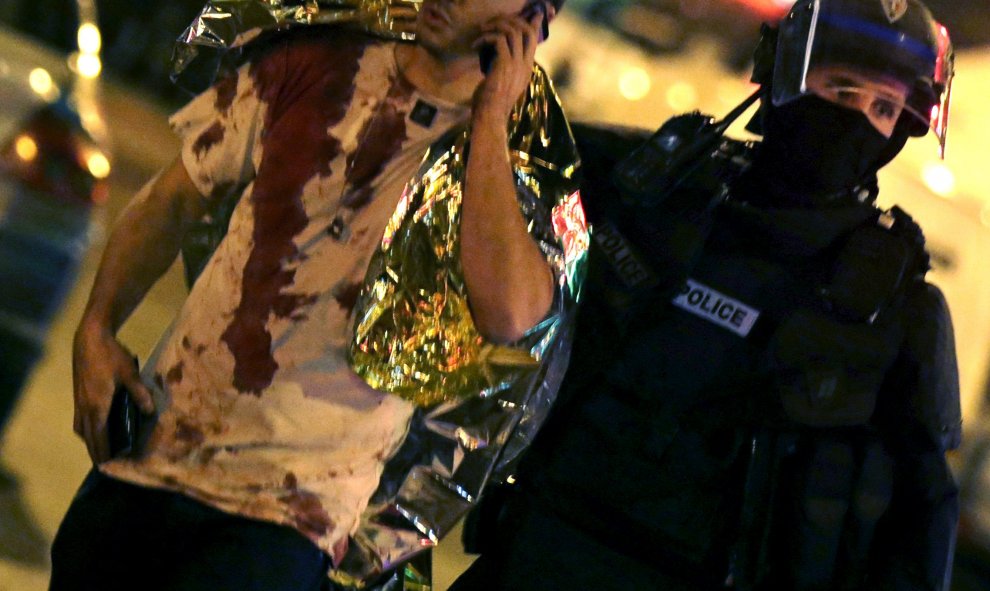 Un policía francés asiste a una víctima de los atentados cubierta de sangre de sangre. REUTERS