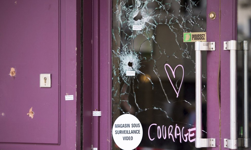 Un corazón y la palabra "coraje" junto a los impactos de bala en uno de los cristale del restaurante Casa Nostra en la Rue de la Fountaine au Roi de París.- EFE