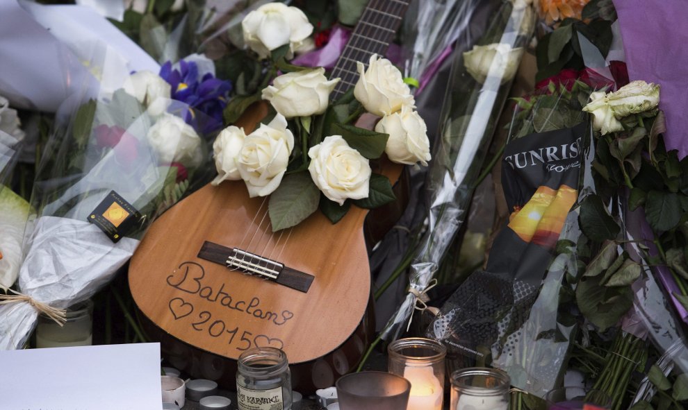 Una guitarra rodeada de flores y velas encendidas que fueron depositadas frente a la sala de fiestas Bataclan en memoria de las víctimas de los atentados del viernes en París.- EFE