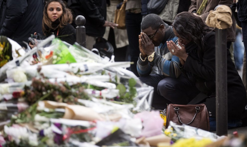 Numerosas personas guardan un minuto de silencio como homenaje a las víctimas de los atentados del viernes en la capital francesa ante el bar le Carillon de París. EFE