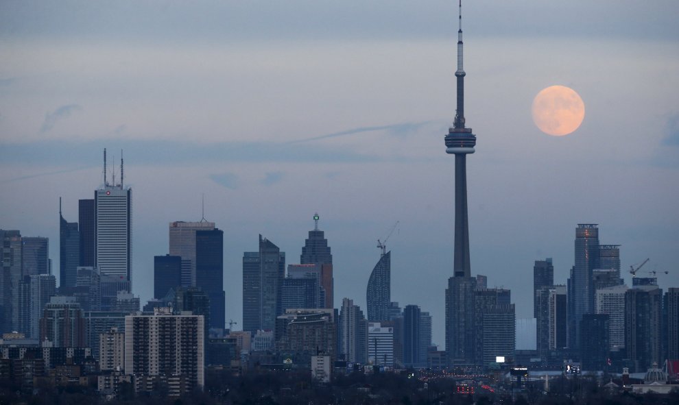 La luna se deja ver detrás de la Torre Nacional de Canadá, un punto de referencia del país. REUTERS / Marcos Blinch