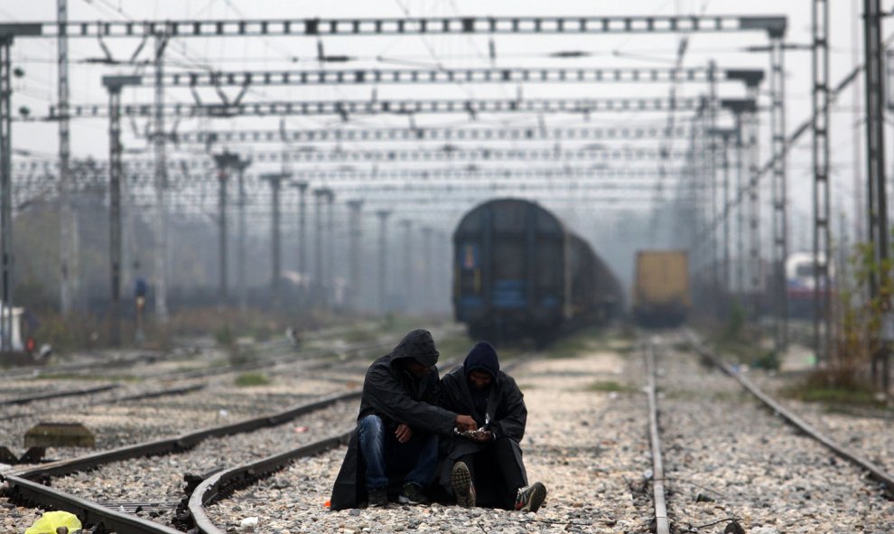 Dos hombres se sientan en las vías del tren mientras emigrantes y refugiados esperan para cruzar la frontera entre Grecia y Macedonia cerca Idomeni el 25 de noviembre de 2015.  AFP / SAKIS MITROLIDIS