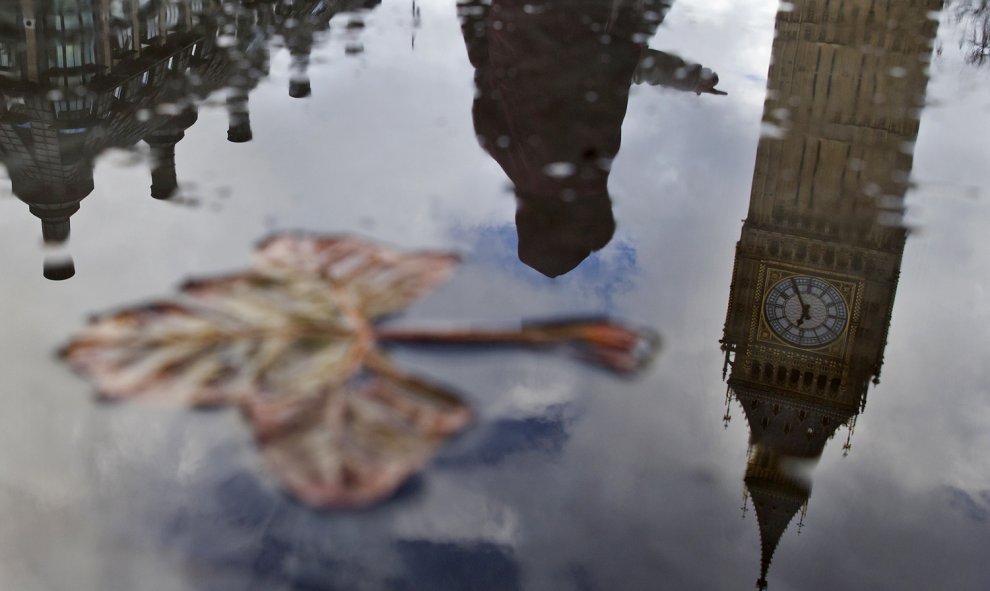 El "Big Ben", se refleja en un charco cerca del Palacio de Westminster, en el centro de Londres, momentos antes de que el el canciller británico de Hacienda, George Osborne, presentase los presupuestos de los departamentos del gobierno para los próximos c