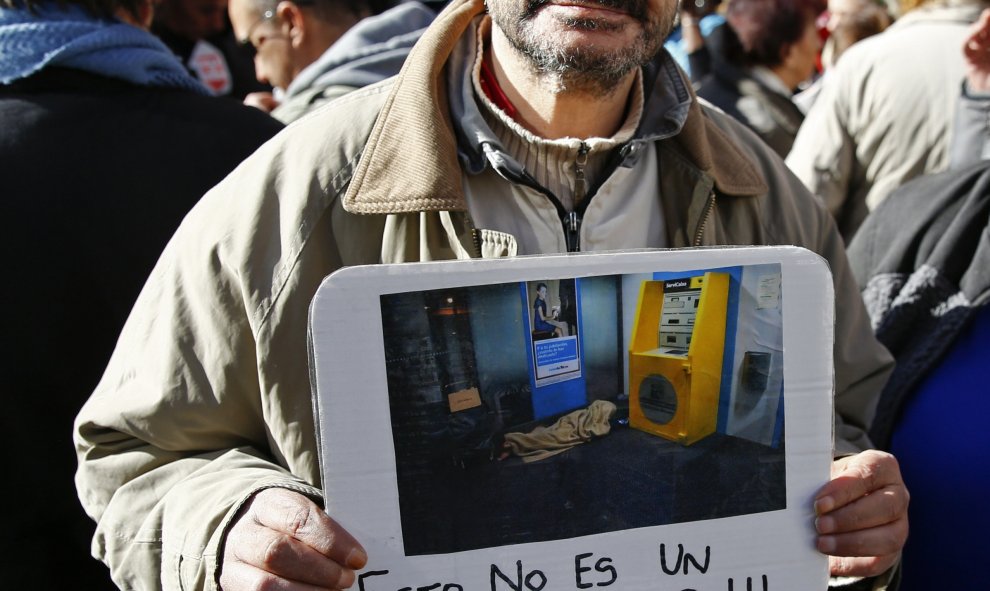 Un hombre enseña una foto de una casa con la frase "Esto no es un hogar", en la protesta convocada por la plataforma "nadie sin hogar" en las calles de Madrid, 26 de noviembre de economía 2015. REUTERS / Paul Hanna