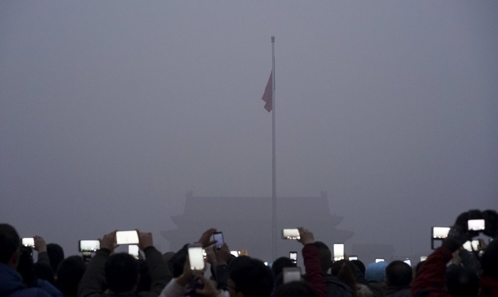 Unos turistas fotografían la ceremonia de la bandera en la plaza de Tiananmen mientras la contaminación sigue sin dar tregua. Pekín, China. REUTERS/Stringer