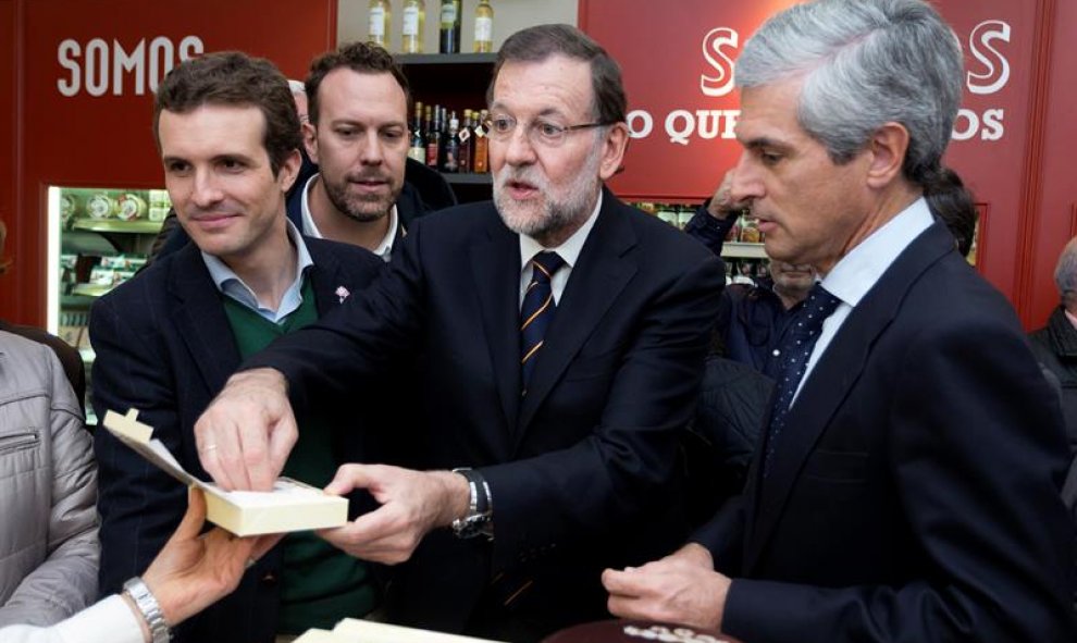Mariano Rajoy, el vicesecretario de Comunicación, Pablo Casado, y Adolfo Suárez Illana, en una conocida tienda de dulces de Ávila prueban las famosas 'yemas de Ávila' durante el acto de campaña celebrado este viernes en la capital abulense. EFE/Raúl Sanch