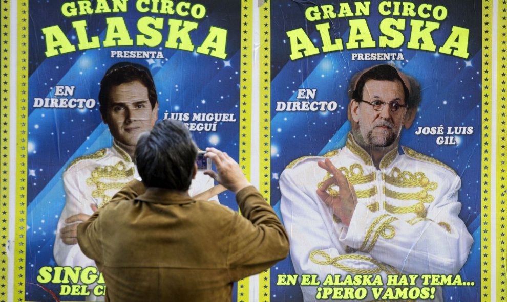 Un hombre toma una fotografía de los cárteles de un circo que actúa estos días en Valencia y en los que alguien ha sustituido las caras de dos de sus artistas por los candidatos a la presidencia del Gobierno Albert Rivera y Mariano Rajoy. EFE/Manuel Bruqu