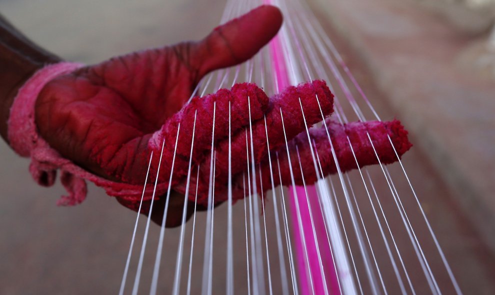 Un trabajador aplica color a las cuerdas que se utilizan para volar cometas en Ahmedabad, India. REUTERS / Dave Amit