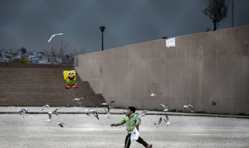 Un pequeño inmigrante juega con un globo de Bob Esponja, cerca del suburbio de refugiados instalado en Atenas. REUTERS/Alkis Konstantinidis