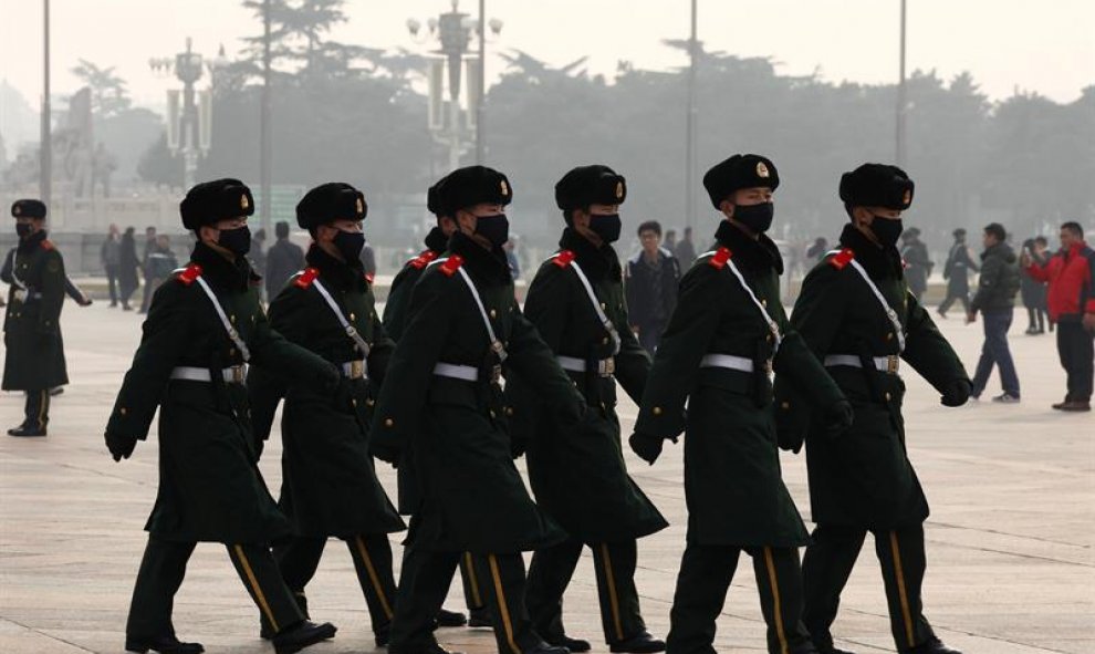Miembros de las fuerzas de seguridad paramilitares chinas patrullan la ciudad de Pekín, ataviados con máscaras para protegerse de la polución. En la capital china, la alerta roja por contaminación implica restricciones severas al tráfico (cada días solo p