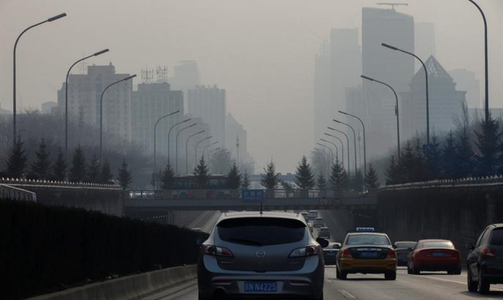 Un vehículo circula por una vía de entrada a Pekín (China), ciudad oculta por espesa niebla de polución. Las autoridades recomiendan a los ciudadanos que reduzcan sus actividades en el exterior y se espera que se suspendan las clases en guarderías y escue