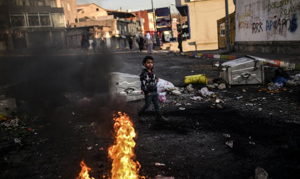 Un niño kurdo camina detrás de las barricadas durante una manifestación en contra de las operaciones de seguridad contra los rebeldes kurdos en las ciudades turcas sudeste Cizre y Silopi./ AFP/BULENT KILIC