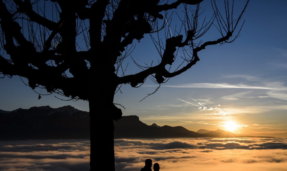 Una pareja contempla la puesta de sol en el lago de Ginebra cubierto de niebla en Chardonne, Suiza hoy 28 de diciembre de 2015. EFE/Jean-Christophe Bott