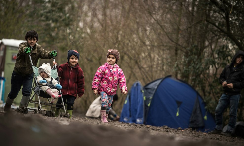 Pequeños refugiados pasean con una sillita de niños entre las tiendas del campamento en Grande-Synthe, en Calais, Francia, el 29 de diciembre de 2015./AFP