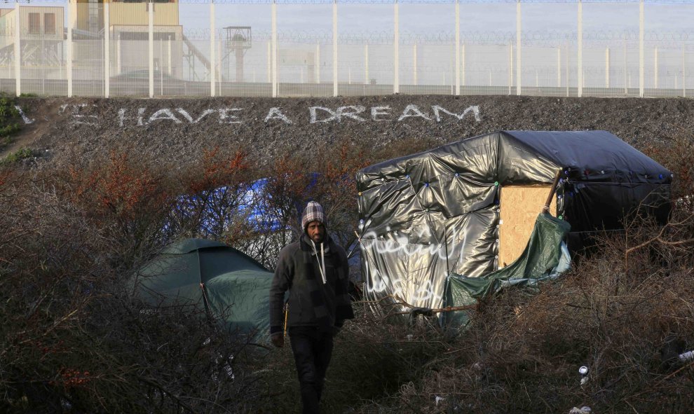 Un refugiado se pasea entre las tiendas en el campamento improvisado en Calais, donde se puede leer al fondo: "Tenemos un sueño",  30 de diciembre 2015 . REUTERS / Pascal Rossignol