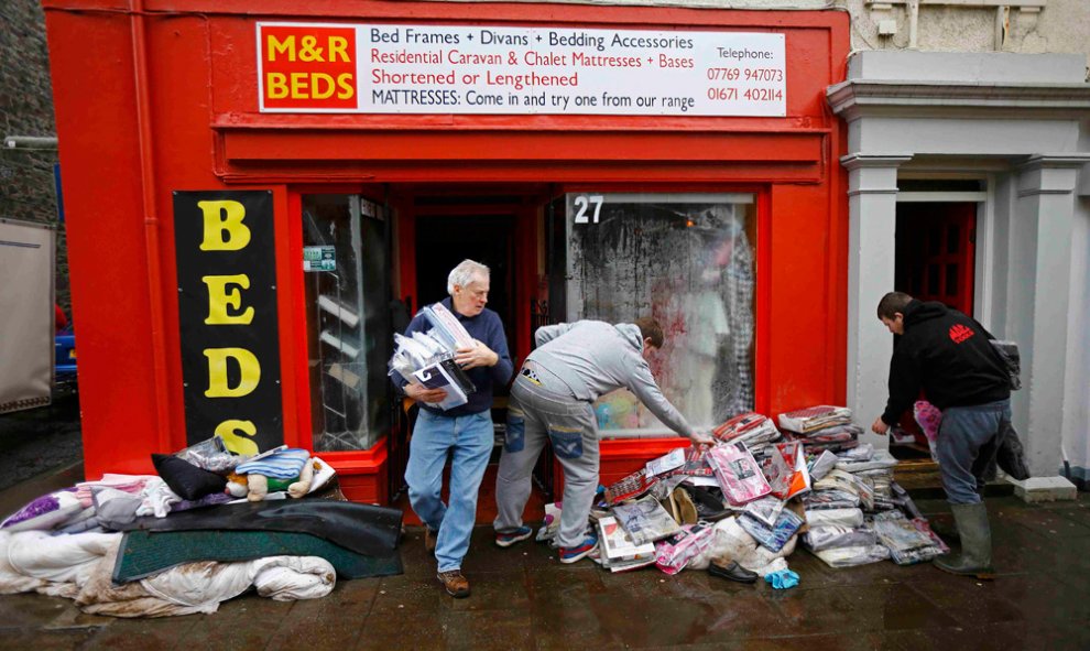 Varias personas recuperan objetos de un local en Newton Stewart (Escocia) tras las riadas. REUTERS/Darren Staples