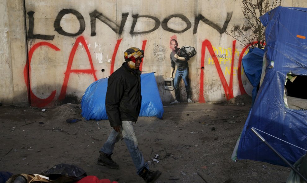 Un inmigrante junto a una pared con un mural pintado por Bansky en el paso de Calais. REUTERS/Pascal Rossignol