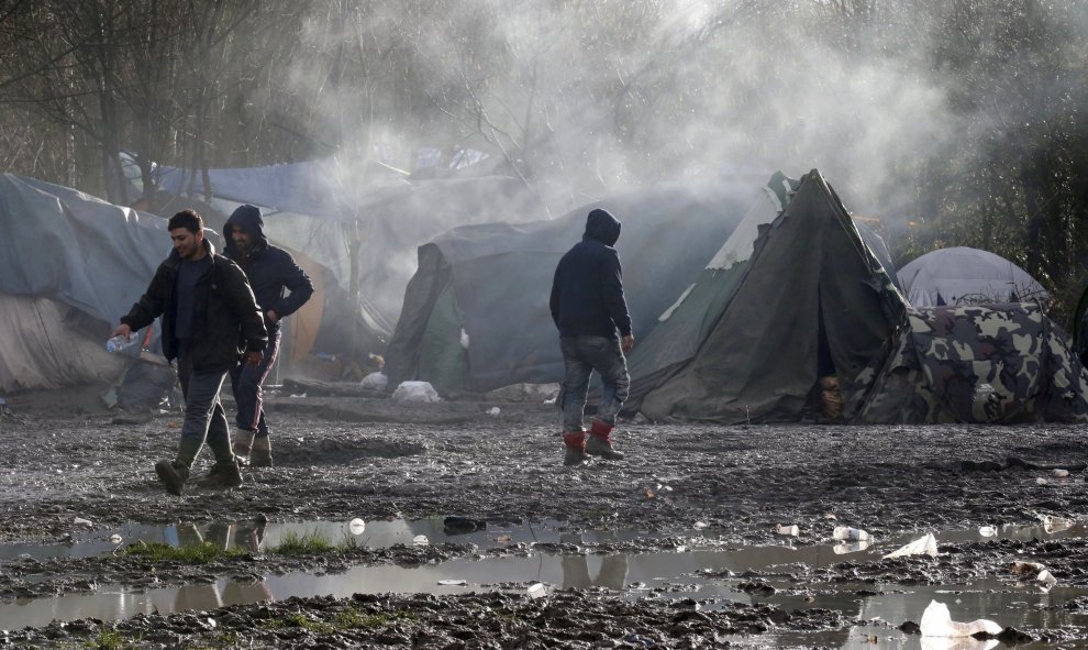 Los inmigrantes caminan por el suelo enfangado del campamento provisional para refugiados de procedentes de Irak, Kurdistán, Irán y Siria, cerca de Dunkerque (Francia). REUTERS / Pascal Rossignol