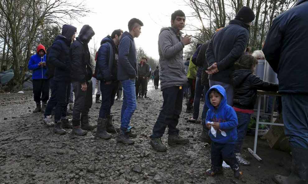 Los inmigrantes hacen cola para en el reparto de comida en el campamento provisional para refugiados de procedentes de Irak, Kurdistán, Irán y Siria, cerca de Dunkerque (Francia). REUTERS / Pascal Rossignol
