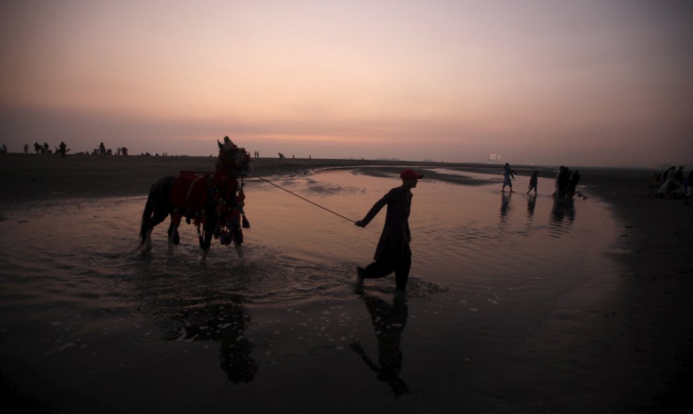 Un hombre camina con su caballo en Karachi, Pakistán