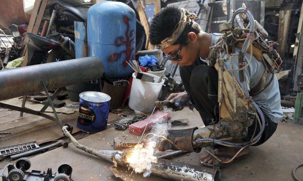 El mecánico Wayan Sumardana, también conocido como Tawan, utiliza lo que él llama un brazo "robótico", creado por él mismo, para soldar parte de una moto de un cliente en su garaje en el pueblo de Nyuh Tebel, Karangasem, Bali, Indonesia 21 de enero 2015.