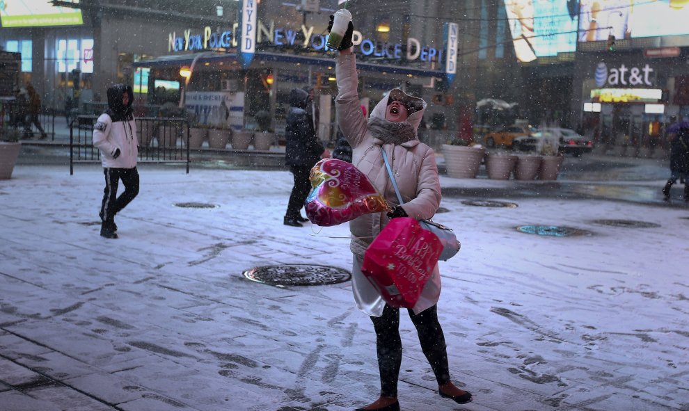 Unas turistas se hacen fotos bajo la nevada en Times Square (Nueva York). /REUTERS