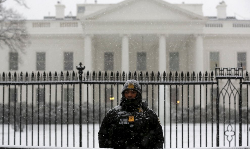 Un agente del servicio de seguridad custodia la verja de la Casa Blanca, cubierta por la nieve. /REUTERS