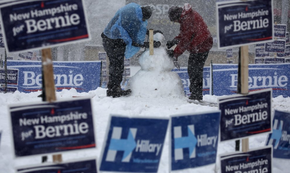 Trabajadores construyen un muñeco de nieve rodeado de carteles electorales. REUTERS/Carlo Allegri