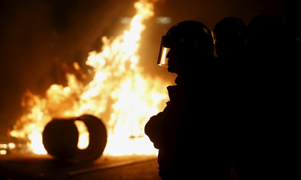 La policía antidisturbios custodia una calle con un incendio provocado por manifestantes en el distrito de Mongkok, en Hong Kong. REUTERS/Bobby Yip