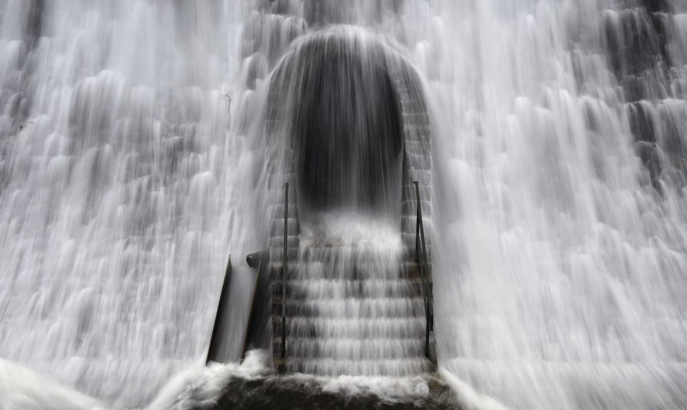 Una cascada de agua por el desbordamiento de la esculsa de Diemeltal cae sobre una puerta en el muro en Diemelsee, Alemania. EFE/Uwe Zucchi