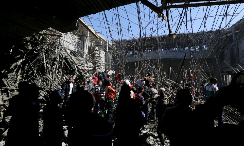 La gente se reúne mientras miembros de la defensa civil palestina hacen una búsqueda de víctimas después de que un techo colapsara en la construcción de la Universidad de al-Aqsa en Khan Younis, en el sur de la Franja de Gaza, 15 de febrero de 2016. De ac