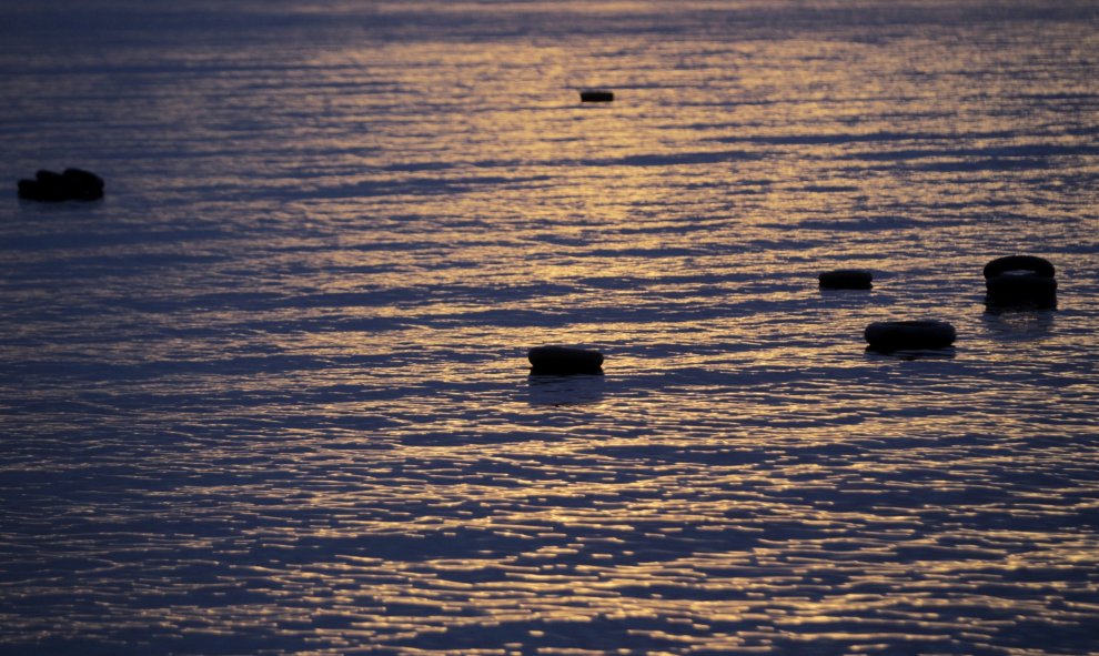 Varios neumáticos, utilizados como salvavidas por refugiados y migrantes, flotan en el mar cerca de la costa de Mytilini, en la isla de Lesbos, Grecia. EFE/Orestis Panagiotou