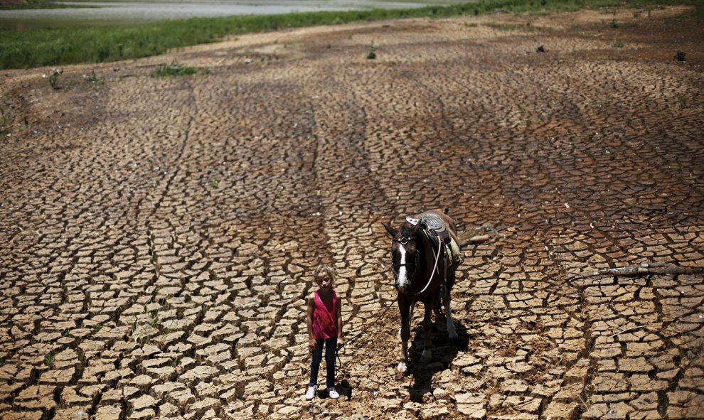 Una niña posa con su caballo en la tierra agrietada por la sequía en la presa Atibainha, en Cantareira, Nazare Paulista, cerca de Sao Paulo, Brasil. REUTERS / Nacho Doce