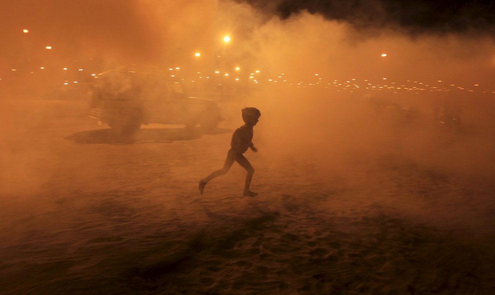 Un niño corre entre el humo procedente tras una fumigación en las orillas del río Ganges, en Allahabad, India. REUTERS/Jitendra Prakash