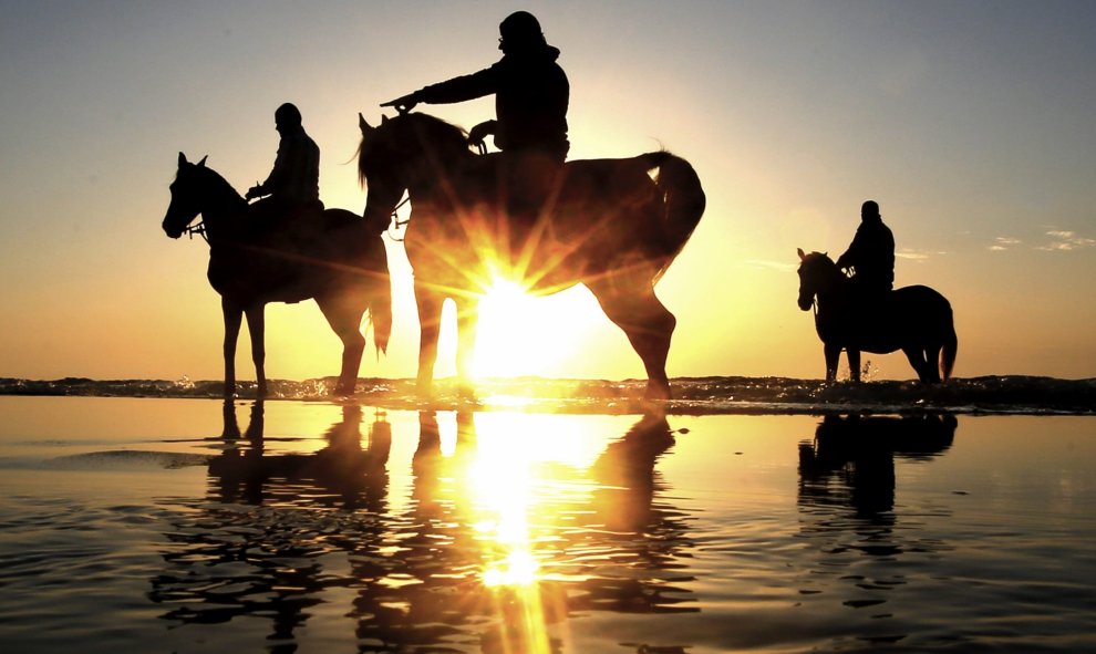 Jóvenes palestinos montando a caballo en la playa al oeste de la Ciudad de Gaza. EFE/MOHAMMED SABER