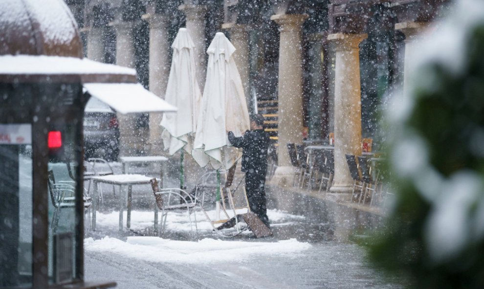 Un hombre recoge la terraza de un bar de Teruel bajo una intensa nevada.EFE/Antonio García