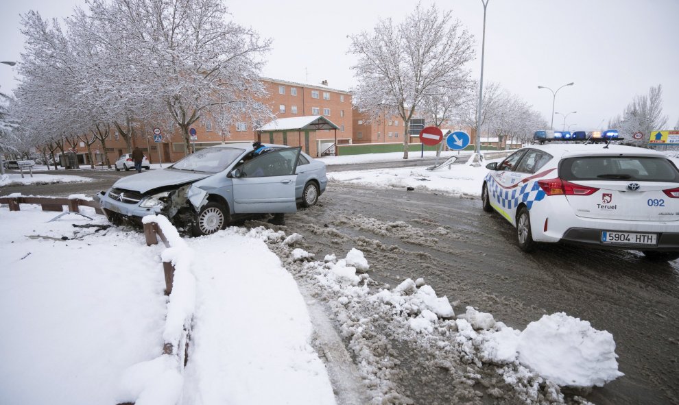 Un efectivo de la Policía Local asiste al conductor de un vehículo accidentado debido a la nieve acumulada hoy en Teruel. EFE/Antonio García
