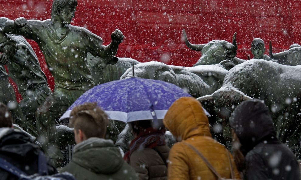 Un grupo de jóvenes camina por una calle de Pamplona donde nieva intensamente desde primeras horas de la tarde. EFe/Villar López