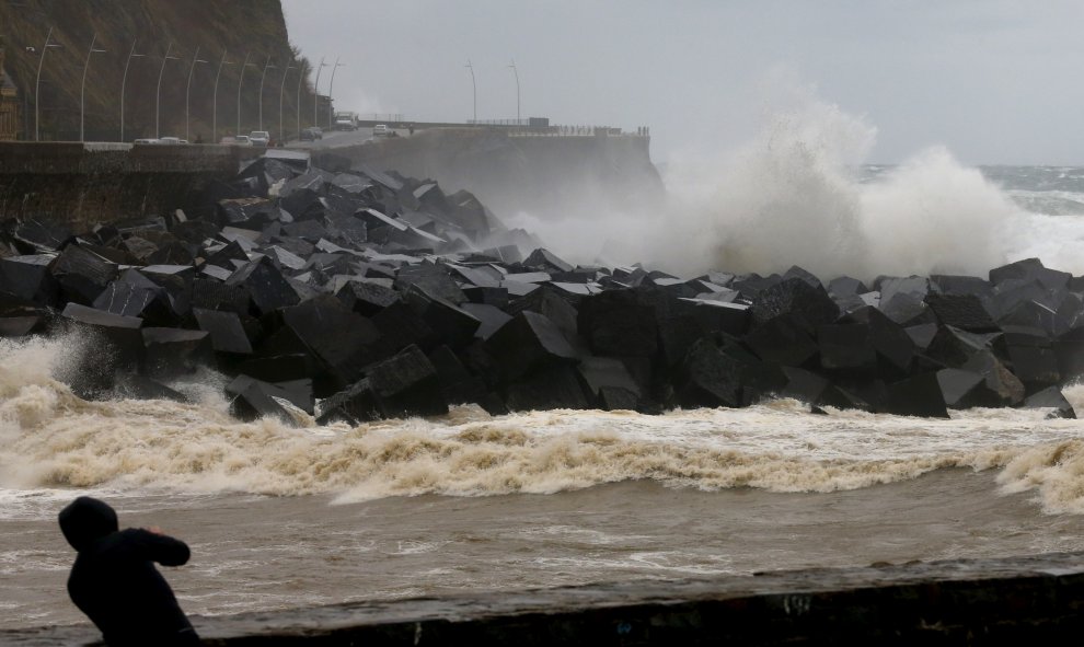 Un hombre toma fotografías del paseo Nuevo de San Sebastián, donde los cielos permanecen cubiertos con lluvias y chubascos generalizados. EFE/Juan Herrero.