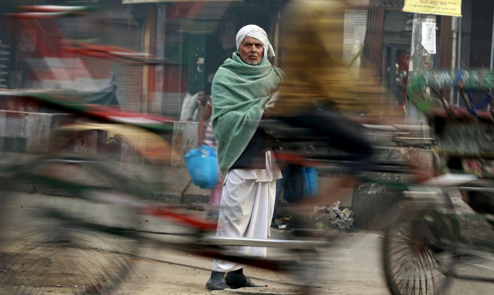 Un hombre observa una bicitaxi que pasa ante él en los cuarteles viejos de Nueva Delhi, India. REUTERS/Cathal McNaughton