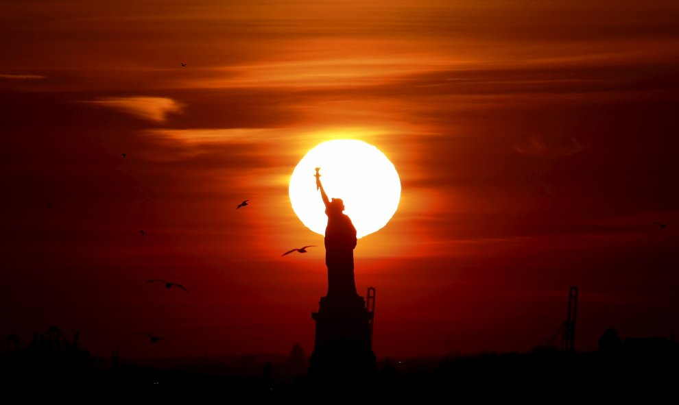 El sol se pone tras la estatua de la Libertad en el puerto de Nueva York. REUTERS/Brendan McDermid