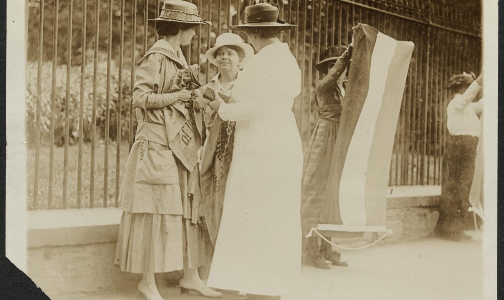 Una mujer policía detiene a las feministas Florencia Youmans (i) y Annie Arniel (d), por negarse a retirar su pancarta reclamando el voto femenino delante de la Casa Blanca, enWashington, en junio de 1917, en una de las fotografías que se conservan en la