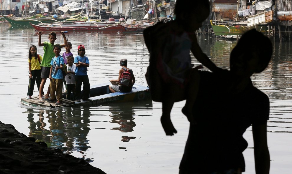 Niños utilizan un barco para cruzar el río Bacoor en Cavite, Filipinas. EFE/Francis R. Malasig