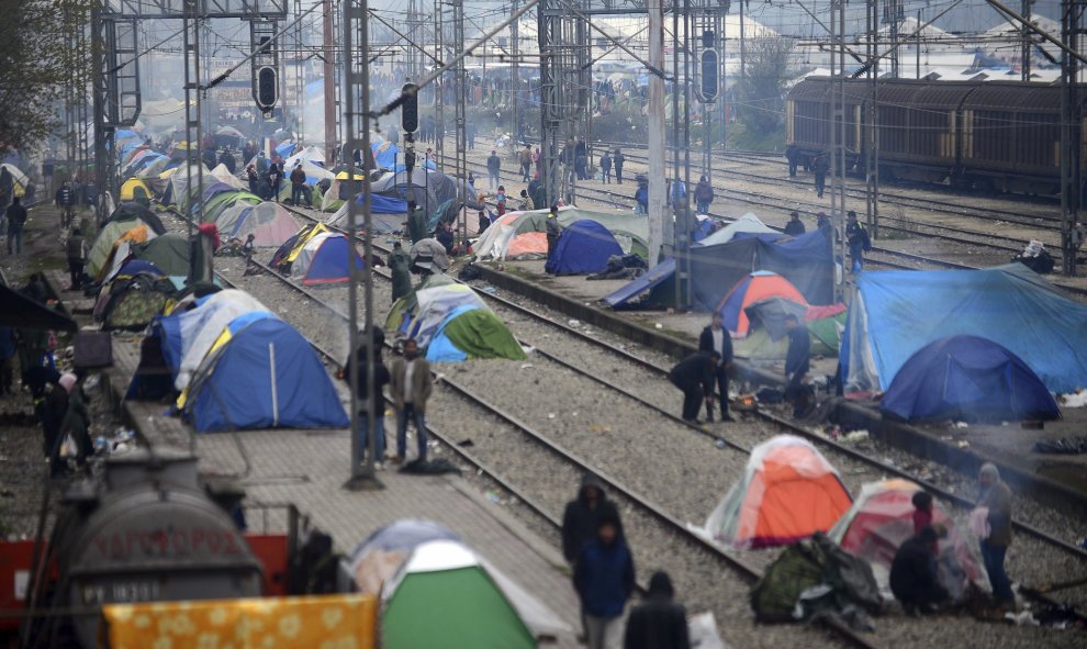 Refugiados transitan por las vías del tren donde se han instalado diversas tiendas de campaña erca de Idomeni (Grecia) en la frontera con Macedonia.- EFE